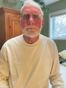 Elderly man with white beard indoors.